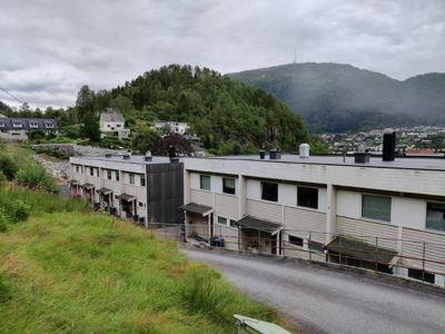 Fotografi av en rekkehusbebyggelse sett fra et høyere nivå, med bakgrunn av fjell og by.