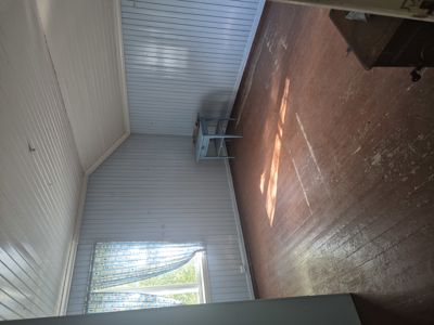 Fotografi av et roms indre med hvite panelvegger, gulv og vindu.