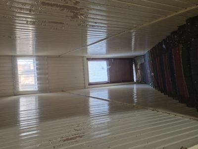 Fotografi av et tomt rom med hvite, ribbede paneler i gulv og tak, samt vinduer på veggen.