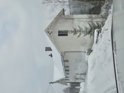 Fotografi av en hvit bygning med snø på taket og i omgivelsene.