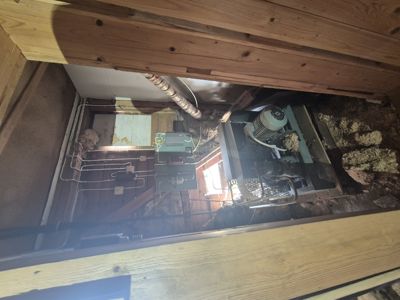 Fotografi av en teknisk installasjon (varmeanlegg/pumpe) i et underlag eller klyng, sett fra innsiden.