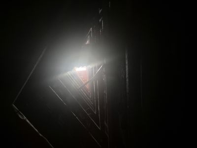 Fotografi av en mørk trapp eller gangvei med lys som kommer inn gjennom et vindu i enden.