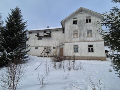 Fotografi av en hvit, trebygning i snø dekket omgivelser.