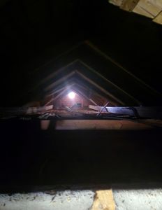 Fotografi av et loft eller takrom sett fra under, med lys som kommer inn gjennom en åpning i taket.