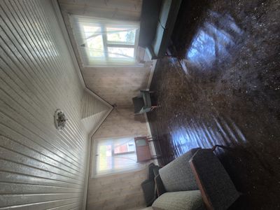 Fotografi av et interiør i en bolig, sannsynligvis stue eller bod, med møbler og vinduer.