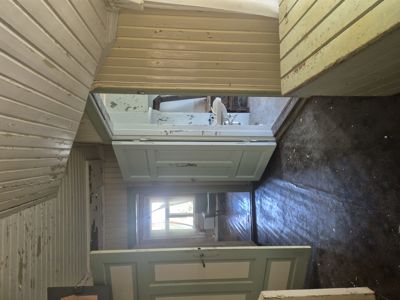 Fotografi av en utegående trapp i en eldre bygning med hvite panelvegger og dører.