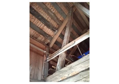 Fotografi av en innvendig takkonstruksjon med store tømmerbjelker og taklister.