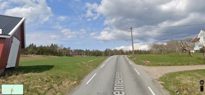 Fotografi tatt fra Google Street View som viser en vei (Enneveien) med en rød skur til venstre og en hvit hytte til høyre.