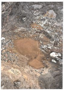 Fotografi av en grøft eller utgravet område med mudder og vann