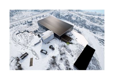 Fotografi av en bygning på en snødekt tomt sett fra luften.