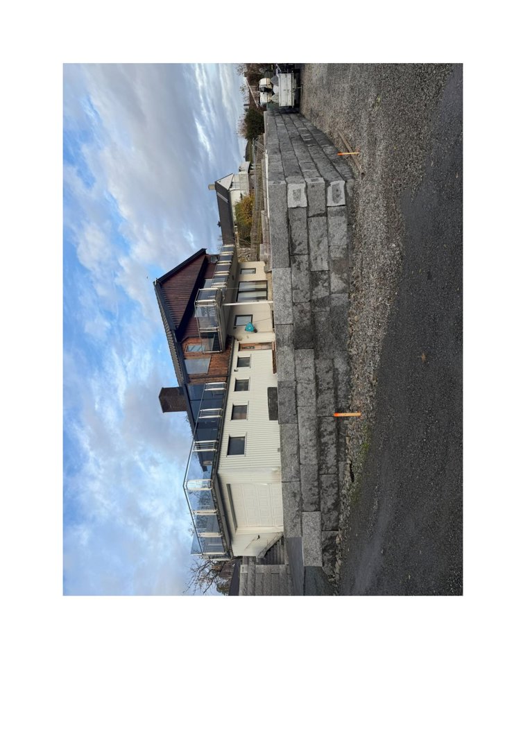 Fotografi av en byggeplass med en ny murt fasade i forgrunnen og eksisterende boliger i bakgrunnen.