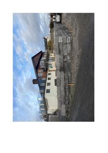 Fotografi av en byggeplass med en ny murt fasade i forgrunnen og eksisterende boliger i bakgrunnen.