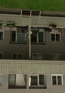 Fotografi av fasaden på en fleretasjes boligbygning, sett fra bakgårdssiden med balkonger og vinduer.