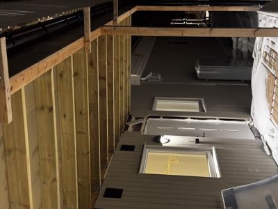 Fotografi av en bygning under oppføring eller ombygging, som viser deler av fasaden, vinduer og takkonstruksjon.