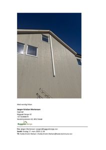 Fotografi av en bygning sett fra nede oppover, som viser fasade, vinduer og takkant mot en blå himmel.