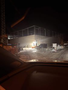 Fotografi av et bygg under oppføring sett fra en bil om natten.
