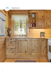 Fotografi av et innredet kjøkken med trepanelvegger, skap og vindu.