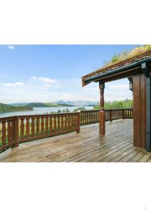 Fotografi av en terrasse med utsikt over vann og fjell.