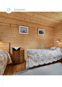 Fotografi av et innredet soverom med trepanelvegger, to senger og møbler.