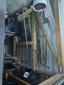 Fotografi av et lagerrom eller utegarderingsrom med diverse byggematerialer, verktøy og utstyr.