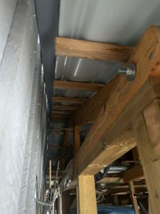 Fotografi av en byggeplass som viser en del av takkonstruksjonen under arbeid. Bildet viser bjelker, takplater og isolasjon.