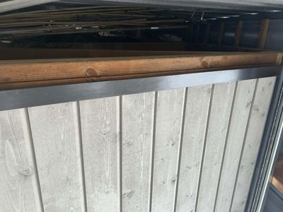 Fotografi av en fasade med horisontale trepaneler og en mørk ramme.