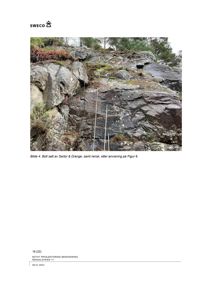 Fotografi av en bergvegg med borehull og stålanker (bolter) satt inn i steinen.