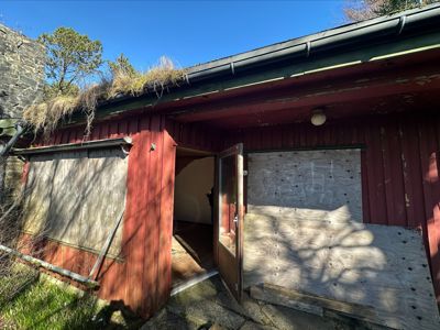 Fotografi av en rød, gammel bygning med etasjegrønt tak og en åpen dør.