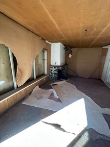 Fotografi av et rom i en bygning som er under renovering eller ombygging, med delvis fjernet gipsplater og gulvbelegg.