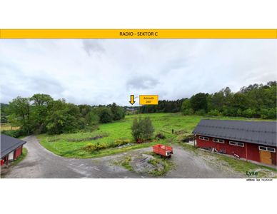 Fotografi av et utendørs område med en rød bygning, en vei og vegetasjon. Bildet inneholder også tekniske annotasjoner som 'RADIO - SEKTOR C' og 'Azimuth 260°'.