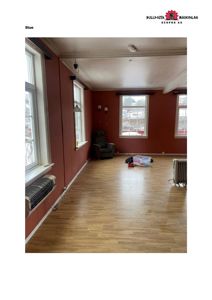 Fotografi av et stuerom med rød maling, lyse gulv og møbler.