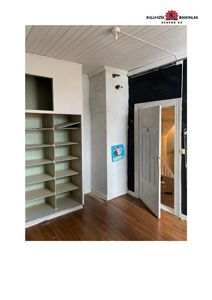 Fotografi av et rom inne i en bygning under ombygging eller renovering, med synlige skap, dør og delvis utrymmede vegger.