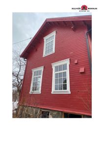 Fotografi av en rød, toetasjes bygning sett fra siden. Bygningen har hvite vinduer og en grå steinfundament. Bildet viser fasaden og takkonstruksjonen.