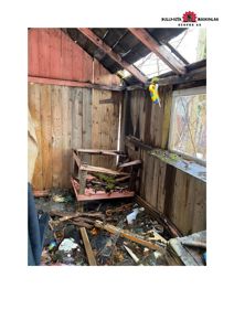 Fotografi av et svært forlatt og ødelagt rom med skrot på gulvet, en ødelagt stol og en skadet takkonstruksjon.