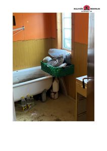 Fotografi av et bad i en bygning under renovering eller ombygging, med synlig badekar, vindu og utstyr.