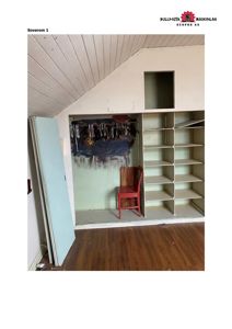 Fotografi av et innvendig rom (soverom) med skrå tak, innbygd garderobe og gulvbelegg.