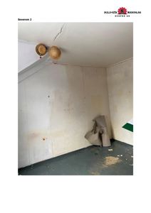 Fotografi av et rom (merket 'Soverom 2') med hvite panelvegger, grå gulv og to spotlykter i taket.