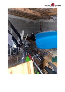 Fotografi av et innendørs rom, sannsynligvis et kjellerrom eller garasje, som er fylt med diverse gjenstander som en sykkel, hyller og en blå badekar.