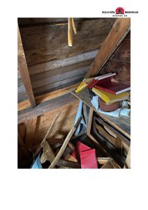 Fotografi av et rom med trekonstruksjon, muligens et loft eller etasjehøyde, med utstyr og bøker på en plate.