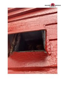 Fotografi av en rød malte fasade med et kvadratisk hull eller åpning.