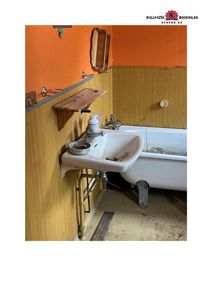 Fotografi av et gammelt, forlatt badrom med en hvit badkar, vask og gulv som ser ut til å være under renovering eller i dårlig stand.