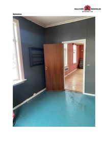 Fotografi av en spisestue med blåmalingte vegger, gulv i ferdigbehandling og en åpen dør som leder til et annet rom.