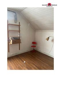 Fotografi av et tomt rom med skrå tak, gulv og innredning.