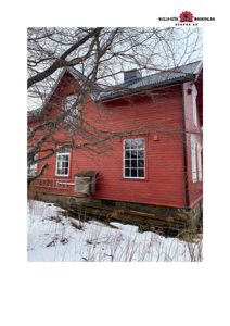 Fotografi av en rød, trepanelt bygning sett fra siden, med snø på bakken og en bar tre i forgrunnen.