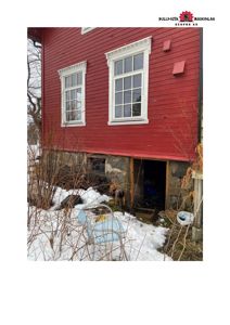 Fotografi av en rød fasett med vinduer og et underbygg i snø.