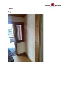 Fotografi av en gang i 1. etasje med hvite panelvegger, en dør med vindue og en tregulv.