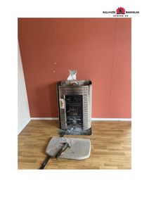 Fotografi av et rom med en gammel kamin og gulv, sannsynligvis fra en byggesak eller renovering.