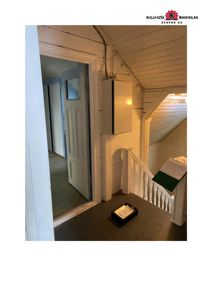 Fotografi av en inngangsparti i en bygning, med åpen dør, trapp og en elektrisk boks på veggen.