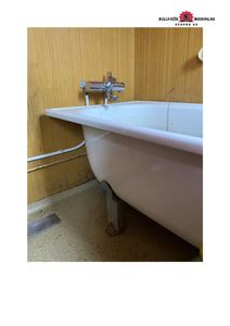 Fotografi av en hvit badkar i et rom med gule panelvegger og gulv. Bildet viser en eksisterende tilstand, ikke en tegning.