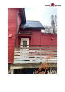 Fotografi av en rød bygning med etasjehus, hvit dør og en uteplass med trelistverk.